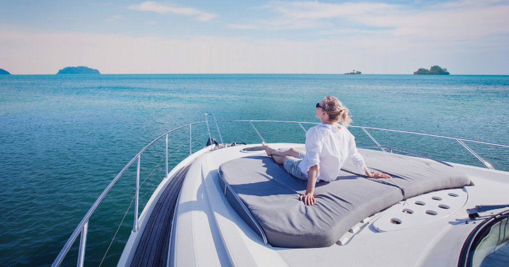 Lady relaxing on yacht while looking over the ocean.