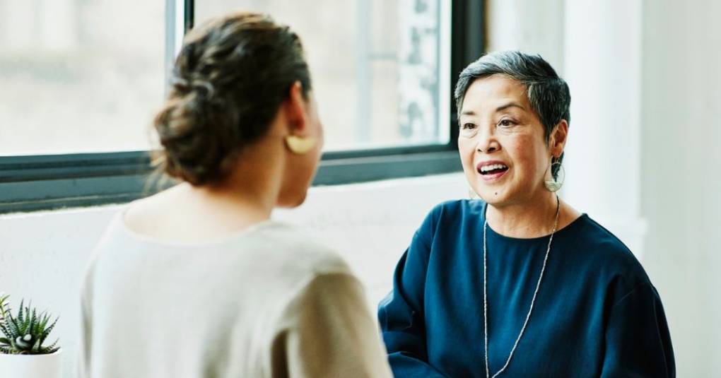 Two ladies facing one another talking.